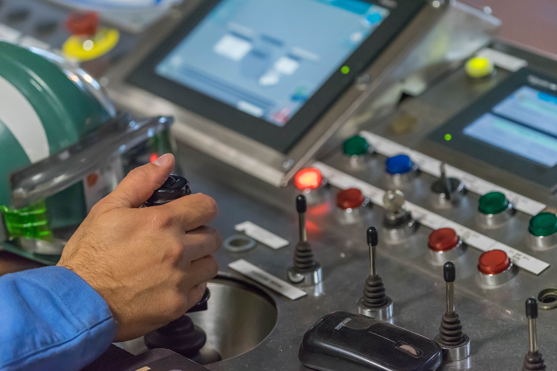 Hand on a controller in an industrial setting.