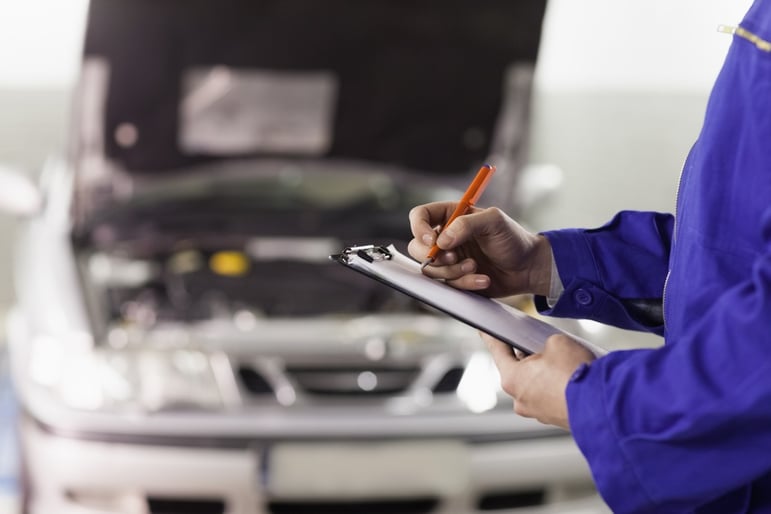 Closeup of a man writing on a clipboard in a garage.jpeg