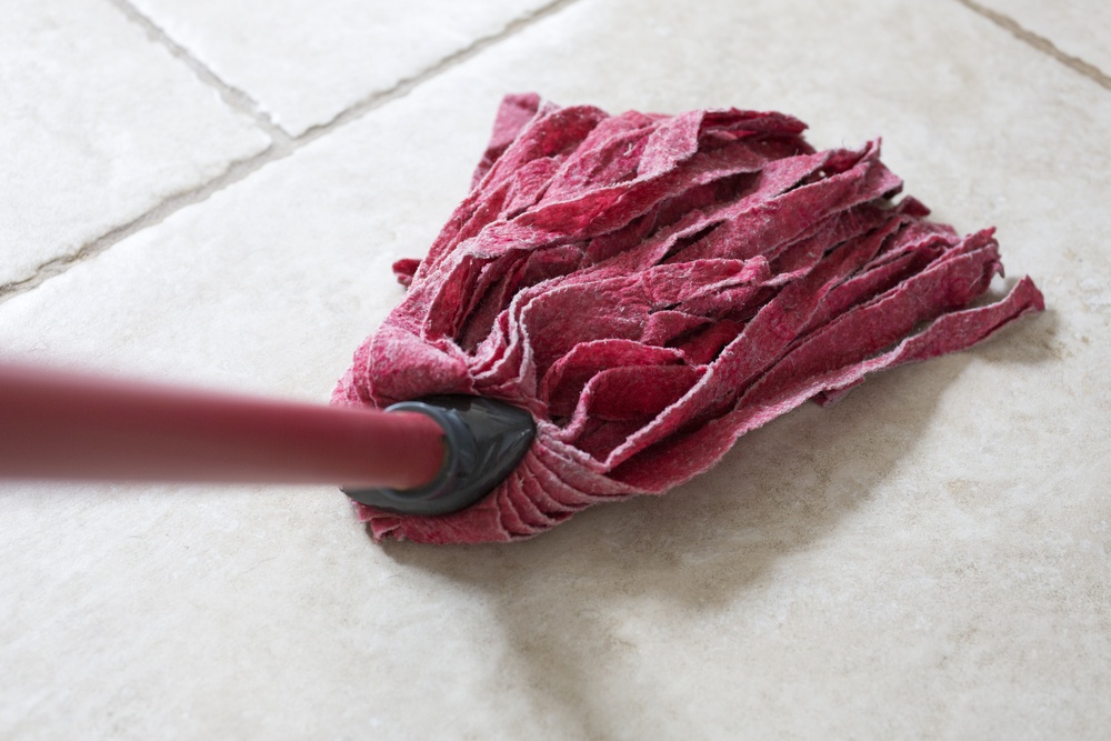 Red kitchen mop being used to clean a floor surface.jpeg